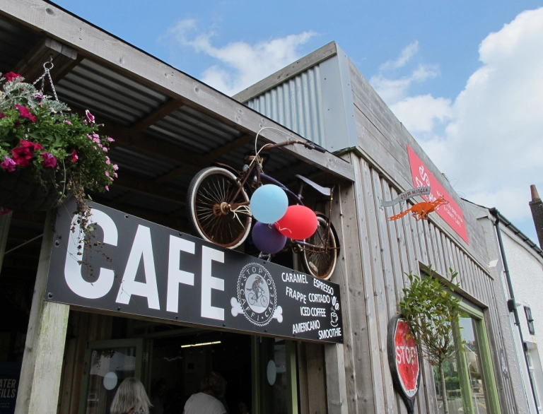 Y tu allan i gaffi gyda beic wedi’i hongian a basged grogi.