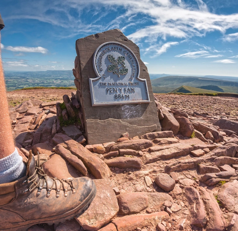 Cerddwr ar gopa Pen y Fan (886m).
