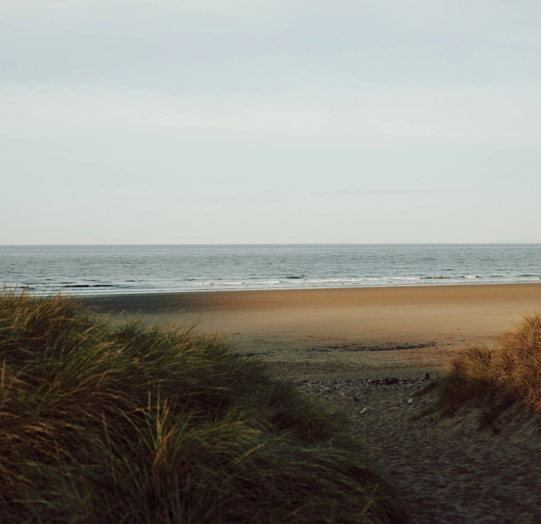 Llun o'r môr, traeth a thwyni tywod