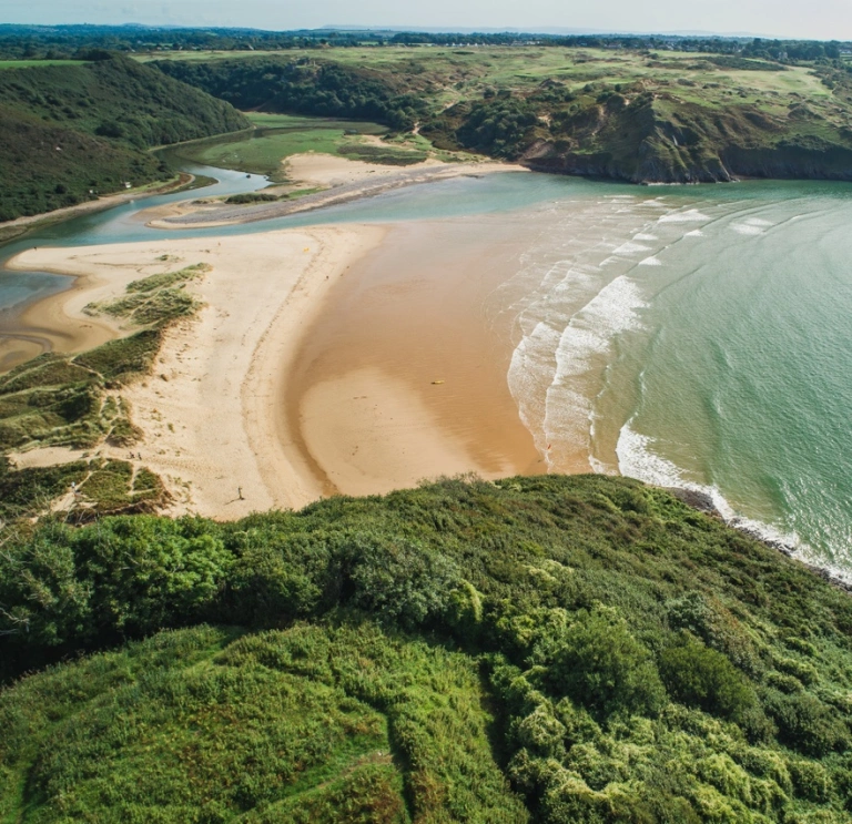 An aerial shot of the cliffs, sea and golden beach.
