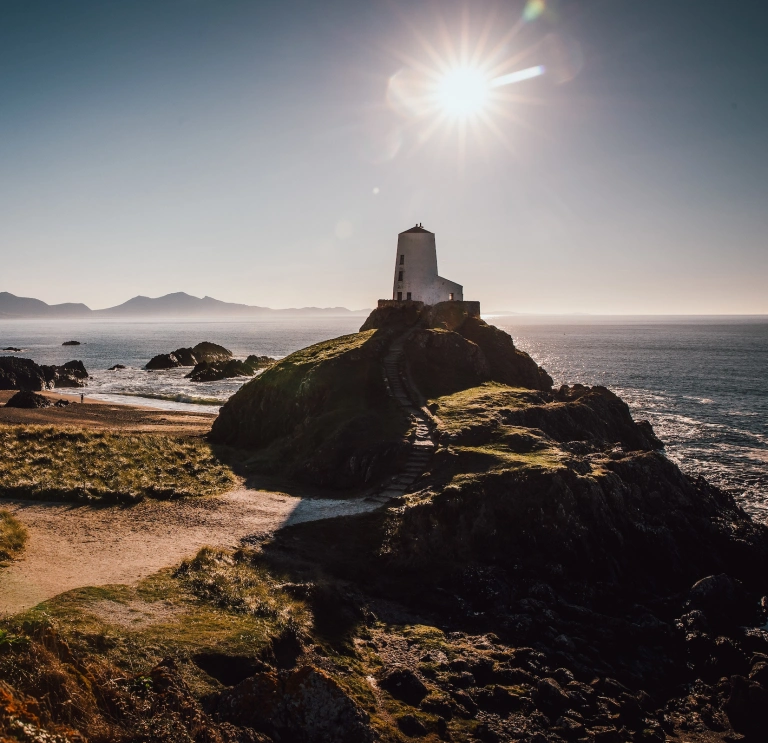 Goleudy Llanddwyn a'r traeth yn haul cryf y gaeaf