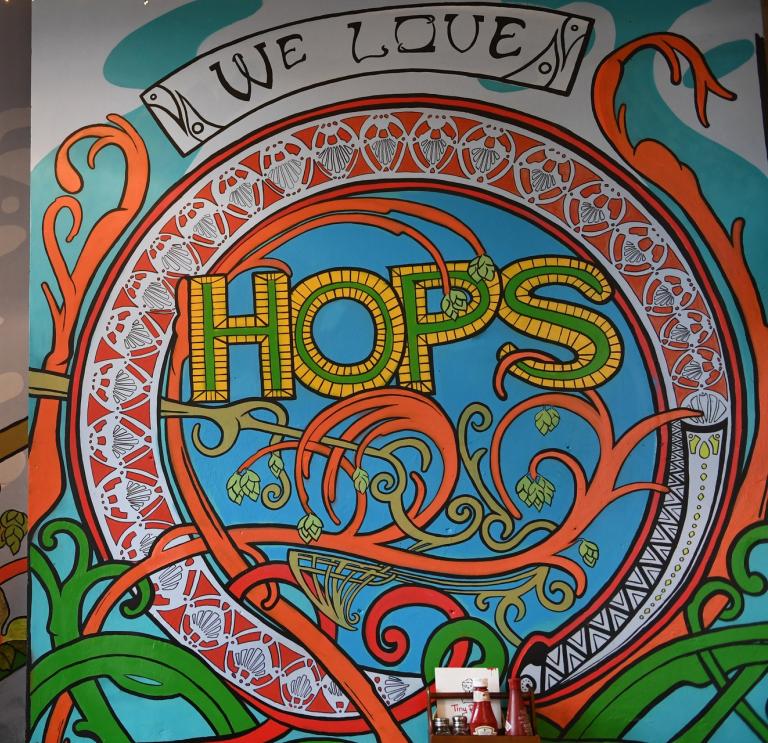 Murlun lliwgar gyda thestun 'We love hops'. 
