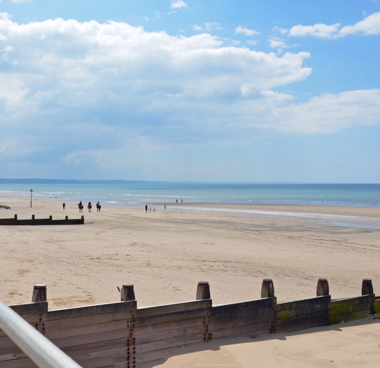 Traeth gyda thywod ar ddiwrnod braf.