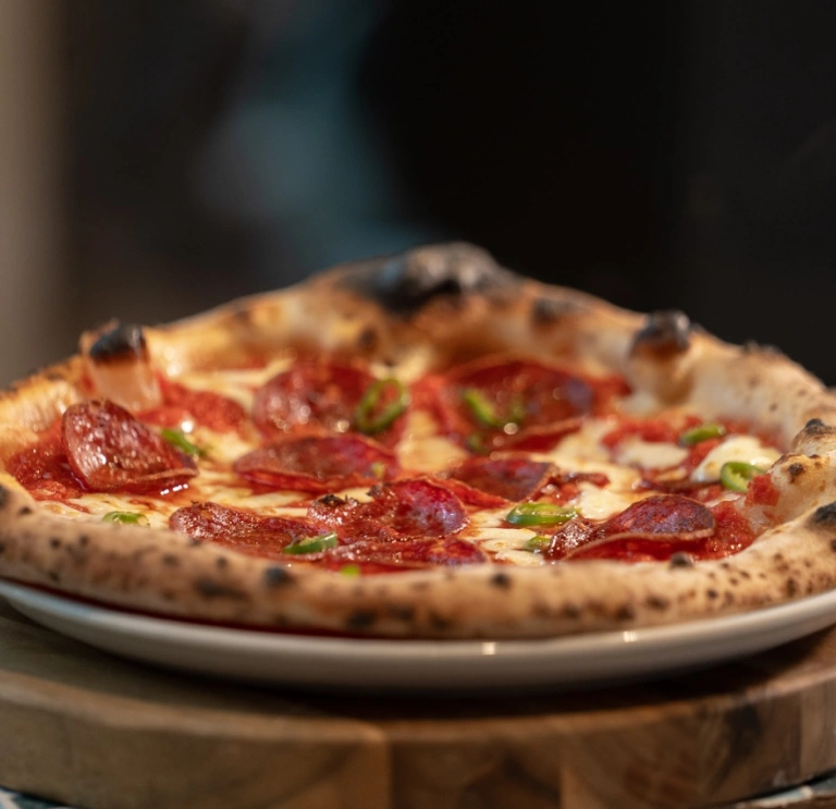 Pizza gyda chig a tsili ar blat wen wedi'i gosod ar darn o bren.