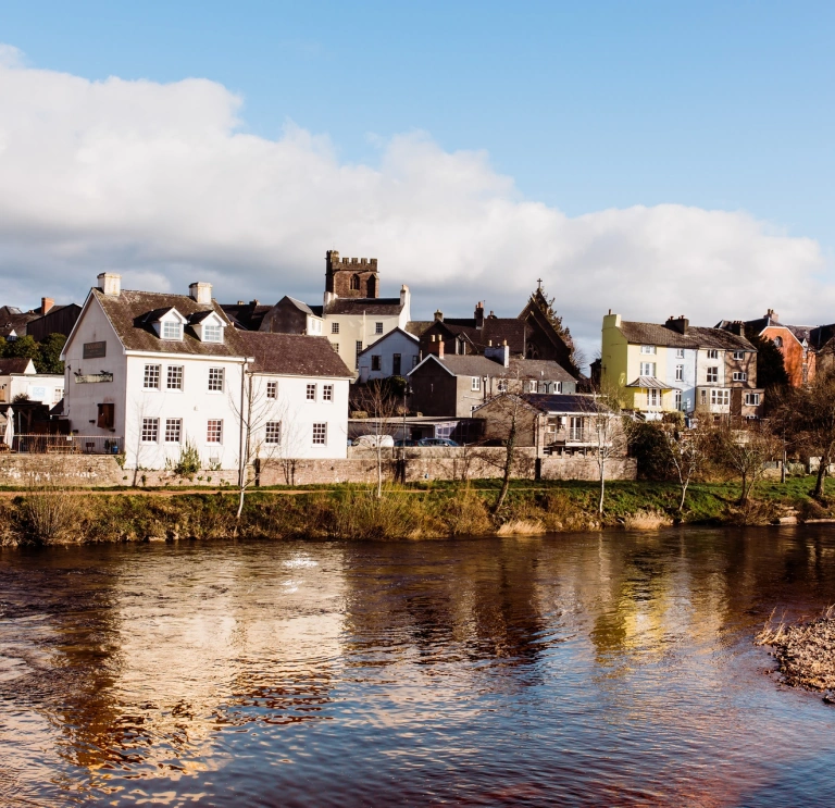 Afon gyda thai ar hyd y lan ac Eglwys Gadeiriol Aberhonddu yn y pellter