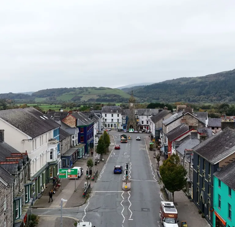 Golygfa awyr o Heol Maengwyn ym Machynlleth, gyda bryniau yn y cefndir.