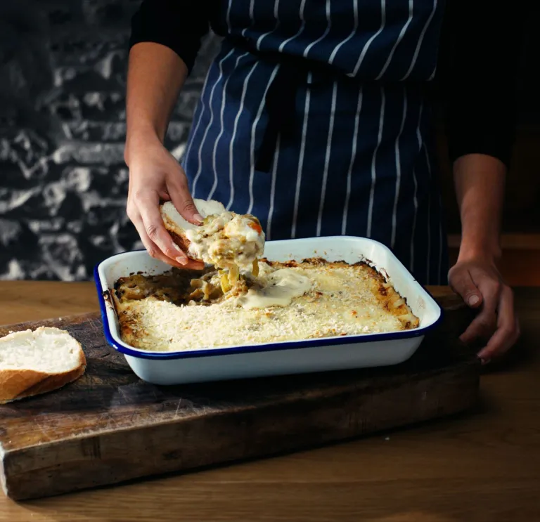 Tegell rostio gyda wyau Môn wedi'u pobi'n ffres, gyda llaw cogydd yn llwytho rhai ar sleisen o frechdan wedi ei dorri