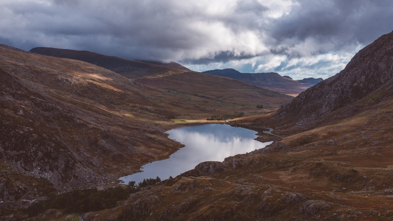 Golygfa o'r llyn wedi'i amgylchynu gan fynyddoedd ar y ddwy ochr ac yn y cefndir