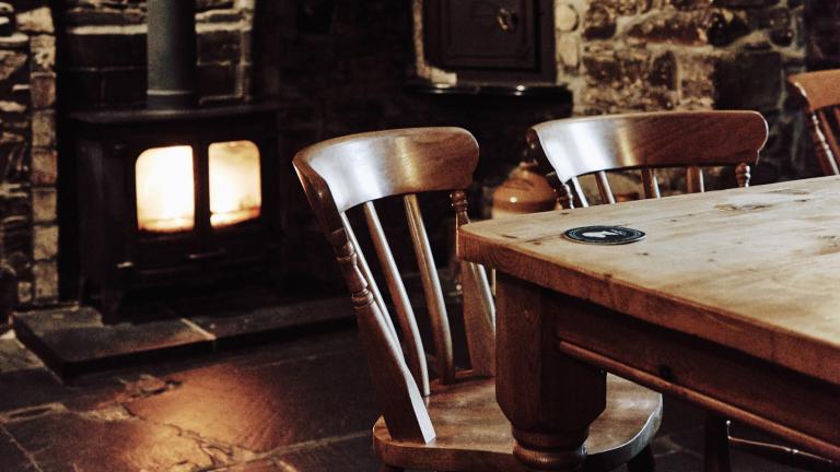 A pub table in front of a log fire built into a stone wall.
