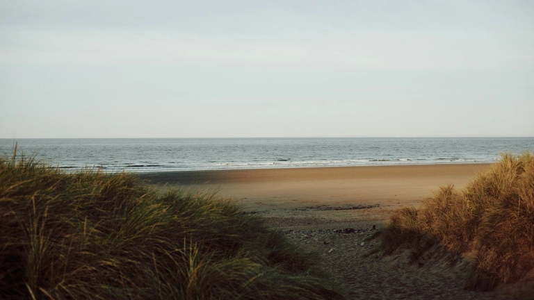 Llun o'r môr, traeth a thwyni tywod