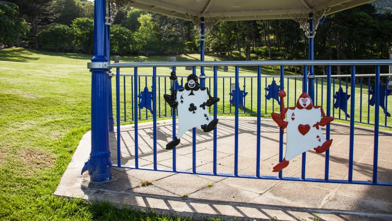 Dau gymeriad o Alys yng Ngwlad Hud ar fandstand yn y parc