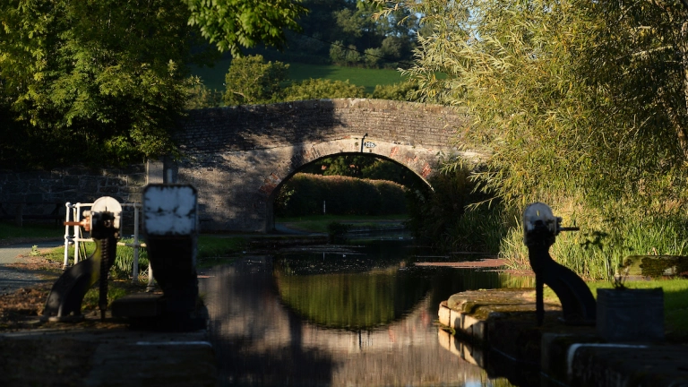 View from a canal lock towards a bridge over the water.