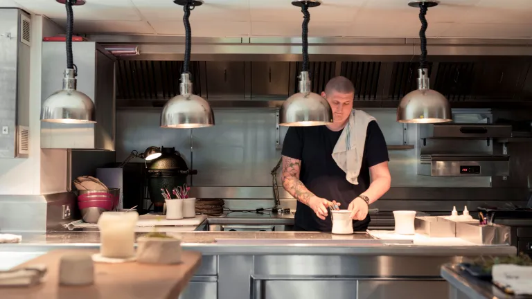 Chef yn paratoi bwyd mewn cegin agored. 