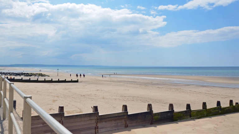 Traeth gyda thywod ar ddiwrnod braf.