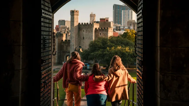 Grŵp o ffrindiau yn edrych allan ar y ddinas o ffenestr y castell 