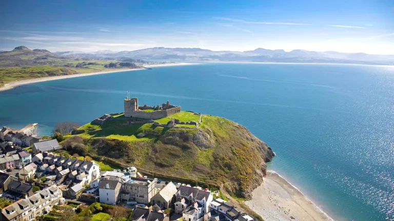 Golygfa o'r awyr o Gastell Cricieth ar y bryn, y dref yn y tu blaen a'r môr a bryniau pell yn y cefndir