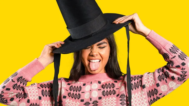 Menyw yn gwisgo het Gymreig ac yn sticio ei thafod allan