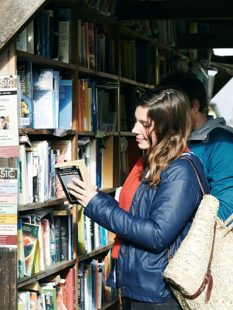 Menyw yn edrych ar lyfrau yn y Gelli Gandryll.