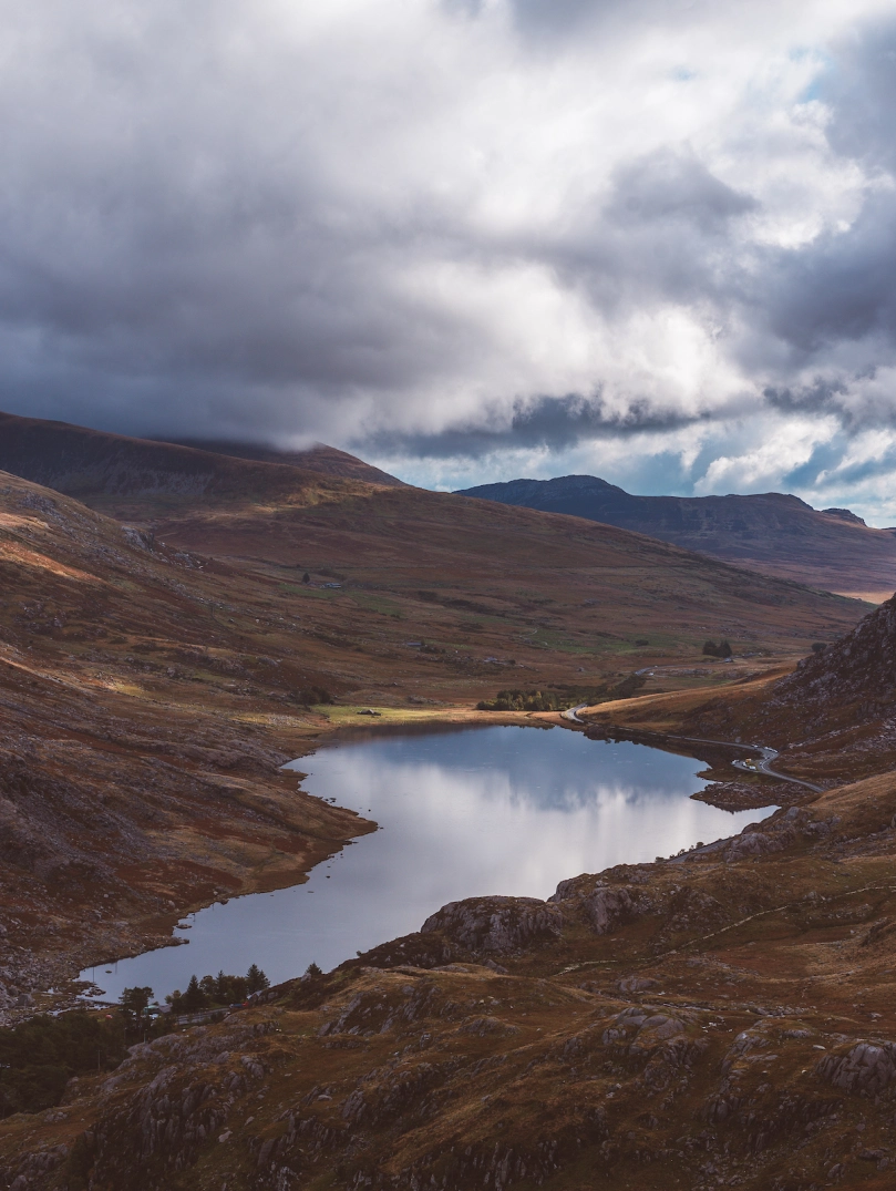 Golygfa o'r llyn wedi'i amgylchynu gan fynyddoedd ar y ddwy ochr ac yn y cefndir