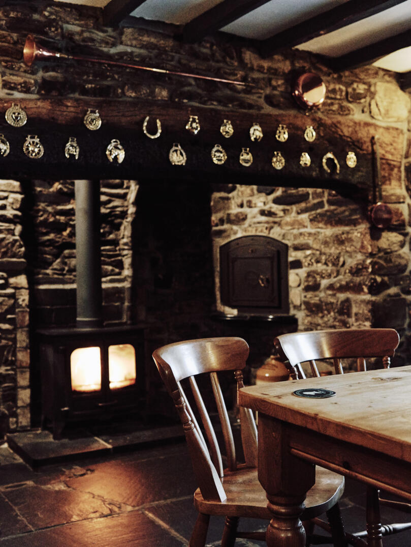 A pub table in front of a log fire built into a stone wall.