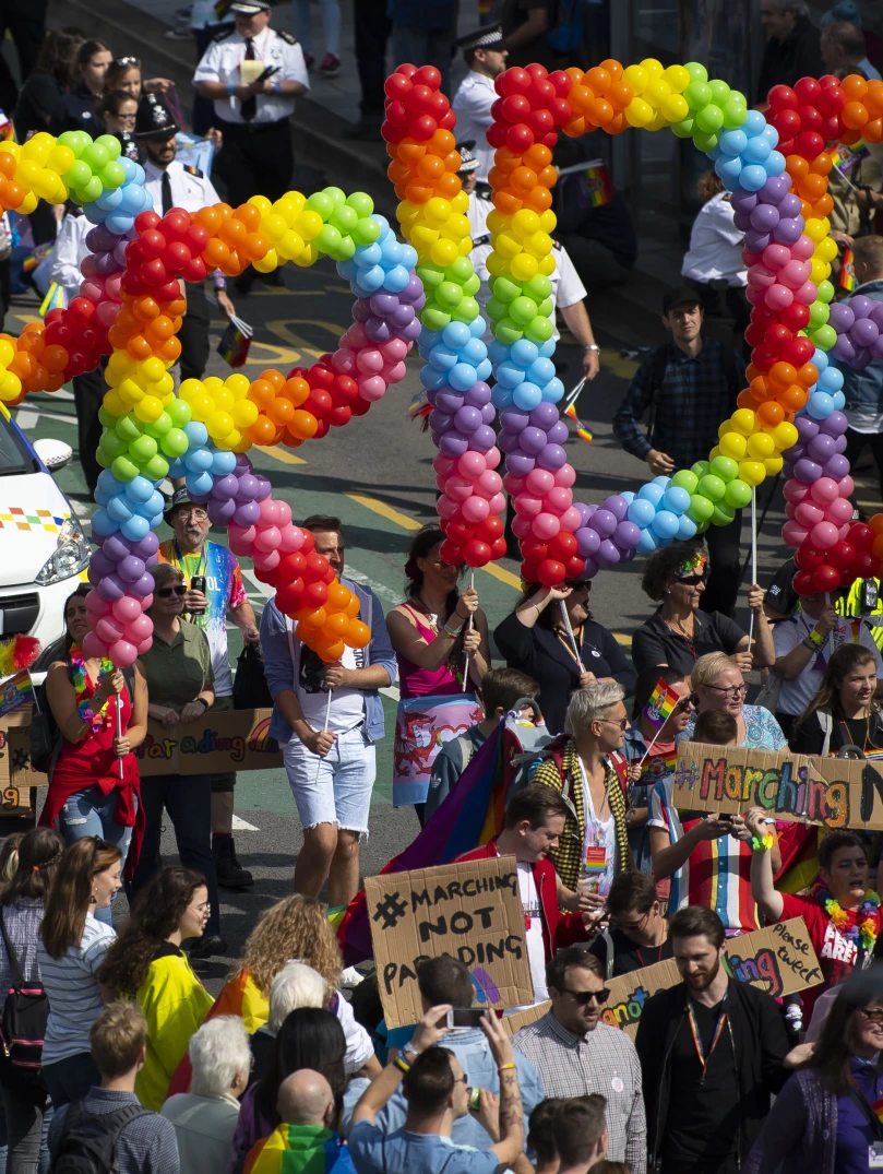 Torf o bobl yn gafael mewn balŵns sy’n dweud Pride.