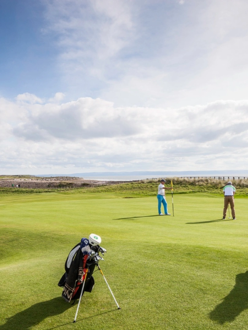 Dau berson yn chwarae golff ar gwrs golff