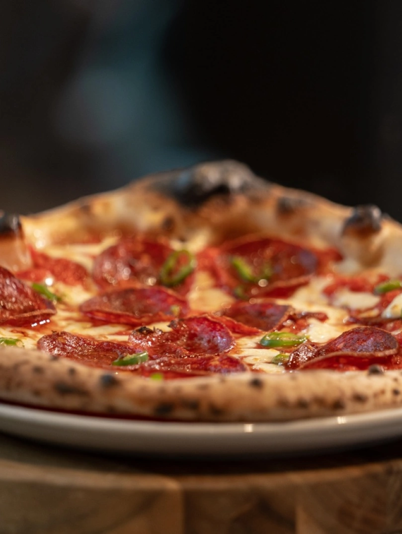 Pizza gyda chig a tsili ar blat wen wedi'i gosod ar darn o bren.