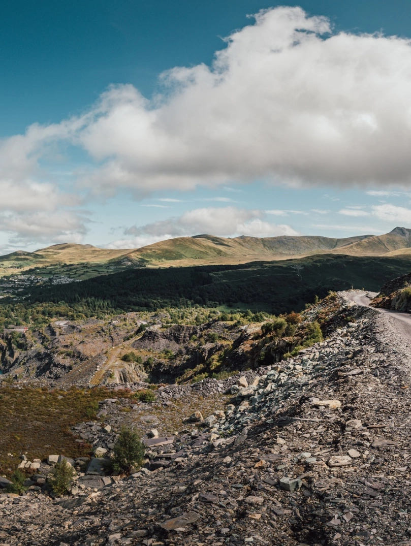 Quarry Kart yn Zip World yn erbyn cefndir o fynyddoedd a phwll glas.
