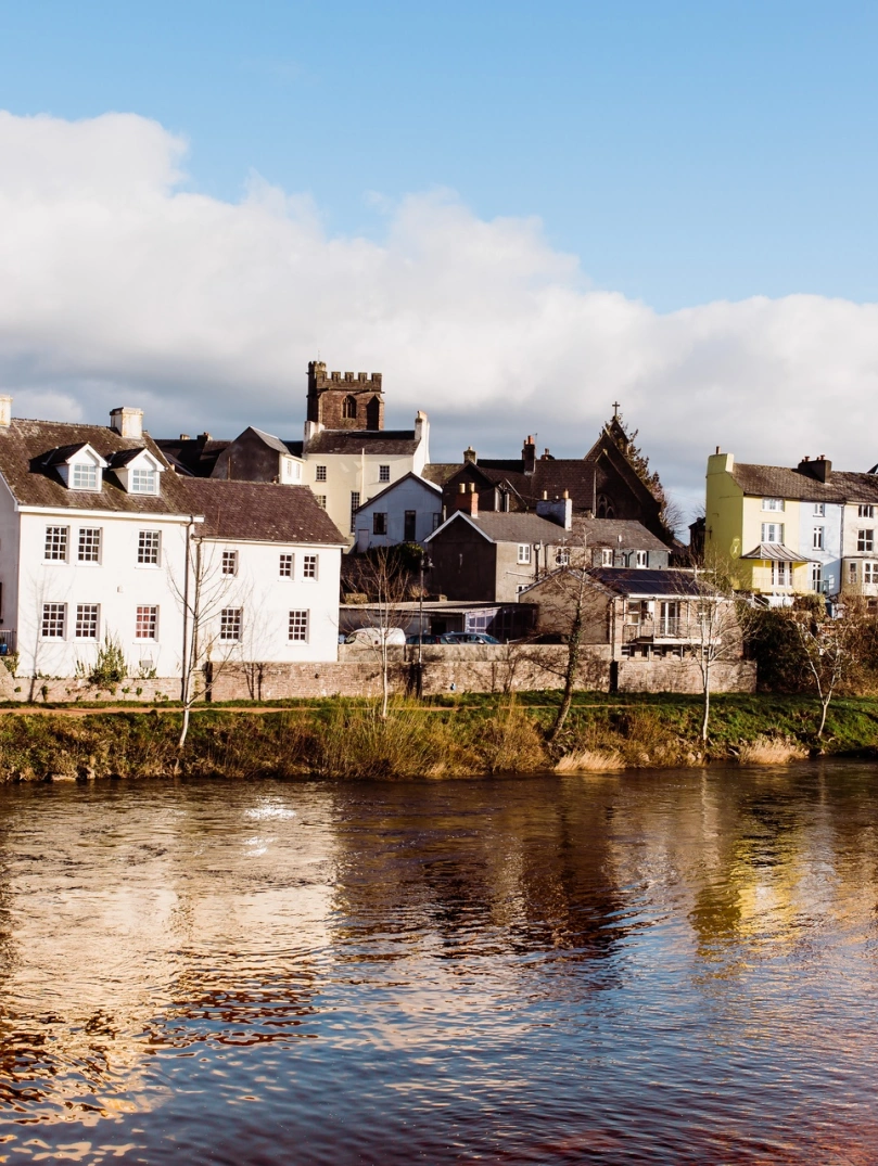 Afon gyda thai ar hyd y lan ac Eglwys Gadeiriol Aberhonddu yn y pellter