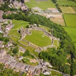 Llun o'r awyr o gastell Dinbych. Mae tai a bryniau gwyrdd o'i gwmpas. 