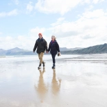 Cwpwl yn cerdded ar draeth Porthdinllaen