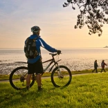 Cyclists on Coast Path at Blackpill at sunrise with Mumbles Head in background