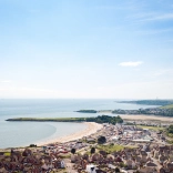 Llun o'r awyr o Ynys y Barri, yn cynnwys y traeth, y parc antur a thai