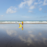 Achubwr bywyd yn sefyll ar y traeth ac yn cadw llygad ar y môr