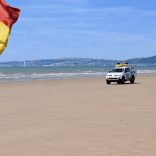 Achubwyr bywyd yn patrolio'r traeth mewn cerbyd