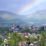 view of town , hills beyond and a rainbow.