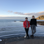 Two women in front of the sea with Constitution Hill in the background.