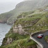 Car yn gyrru ar hyd ffordd droellog gyda'r môr ar yr ochr chwith