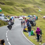 Beicwyr a gwylwyr yn leinio ffordd fynyddig.