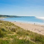 Traeth, gyda thwyni tywod yn y tu blaen, a'r môr yn y cefndir