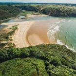 An aerial shot of the cliffs, sea and golden beach.