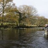 Dyn yn pysgota mewn afon. 