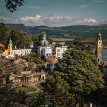 Golygfa o bentref Portmeirion o’r awyr gyda’r môr a’r mynyddoedd yn y cefndir.