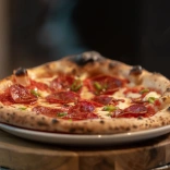 Pizza gyda chig a tsili ar blat wen wedi'i gosod ar darn o bren.