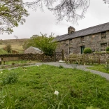 Tu allan i hen ffermdy carreg a gardd o'i flaen.