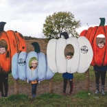Plant tu mewn i addurniadau pwmpen yn sefyll am y llun.