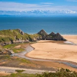 Llanw allan ym Mae'r Tri Chlogwyn gyda thraeth tywodlyd.