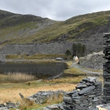 Llyn gyda mynyddoedd o'i amgylch a wal lechi.