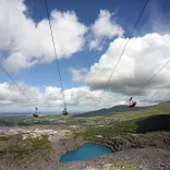 Tri pherson ar bedair weiren wib dros lyn glas dwfn mewn chwarel.