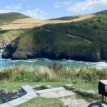 Person yn sefyll gyda beic yn edrych allan dros y môr